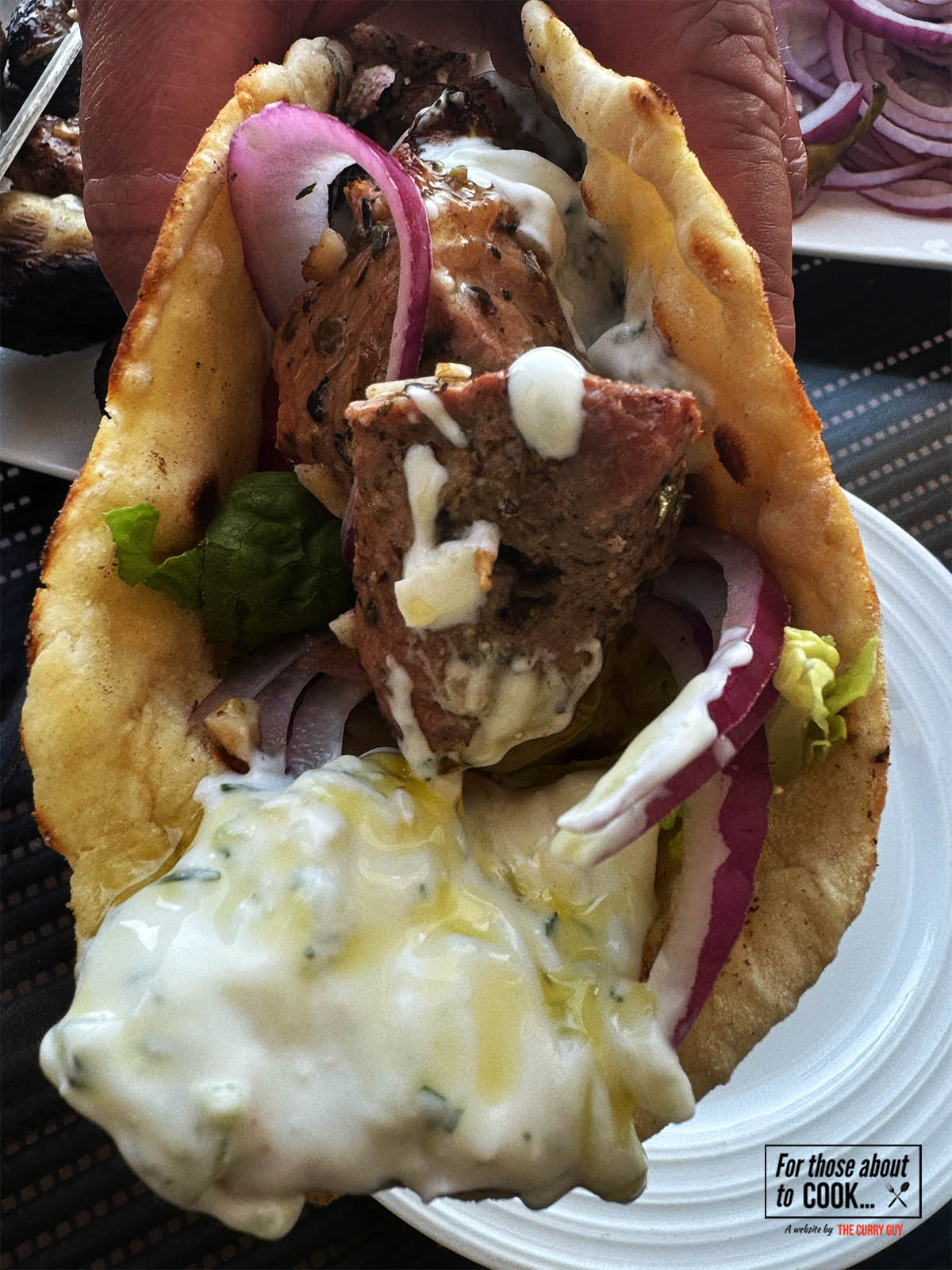 Pork souvlaki wrapped up in a pita with tzatziki and salad vegetables.