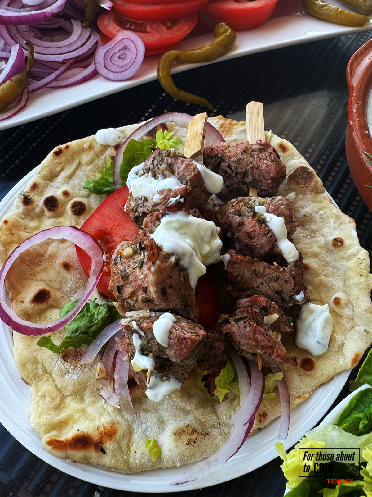 Pork souvlaki on a pita with tzatziki and salad vegetables.