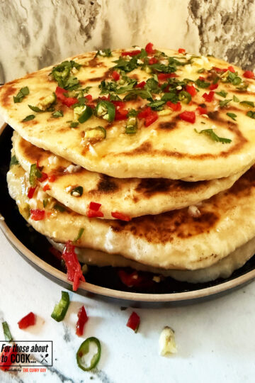Chili cheese naan breads stacked and topped with garlic butter and chillies
