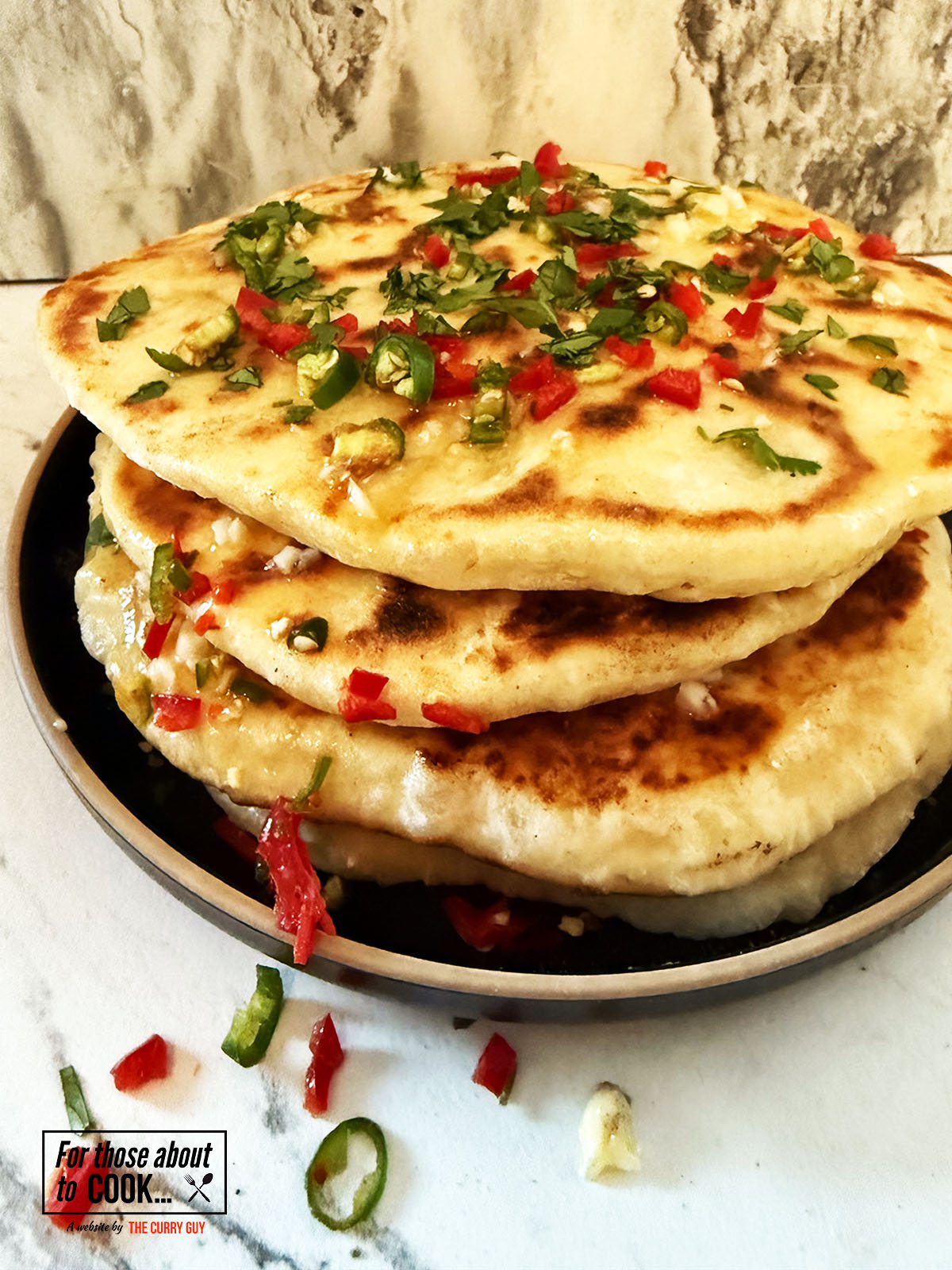 Chili cheese naan breads stacked and topped with garlic butter and chillies