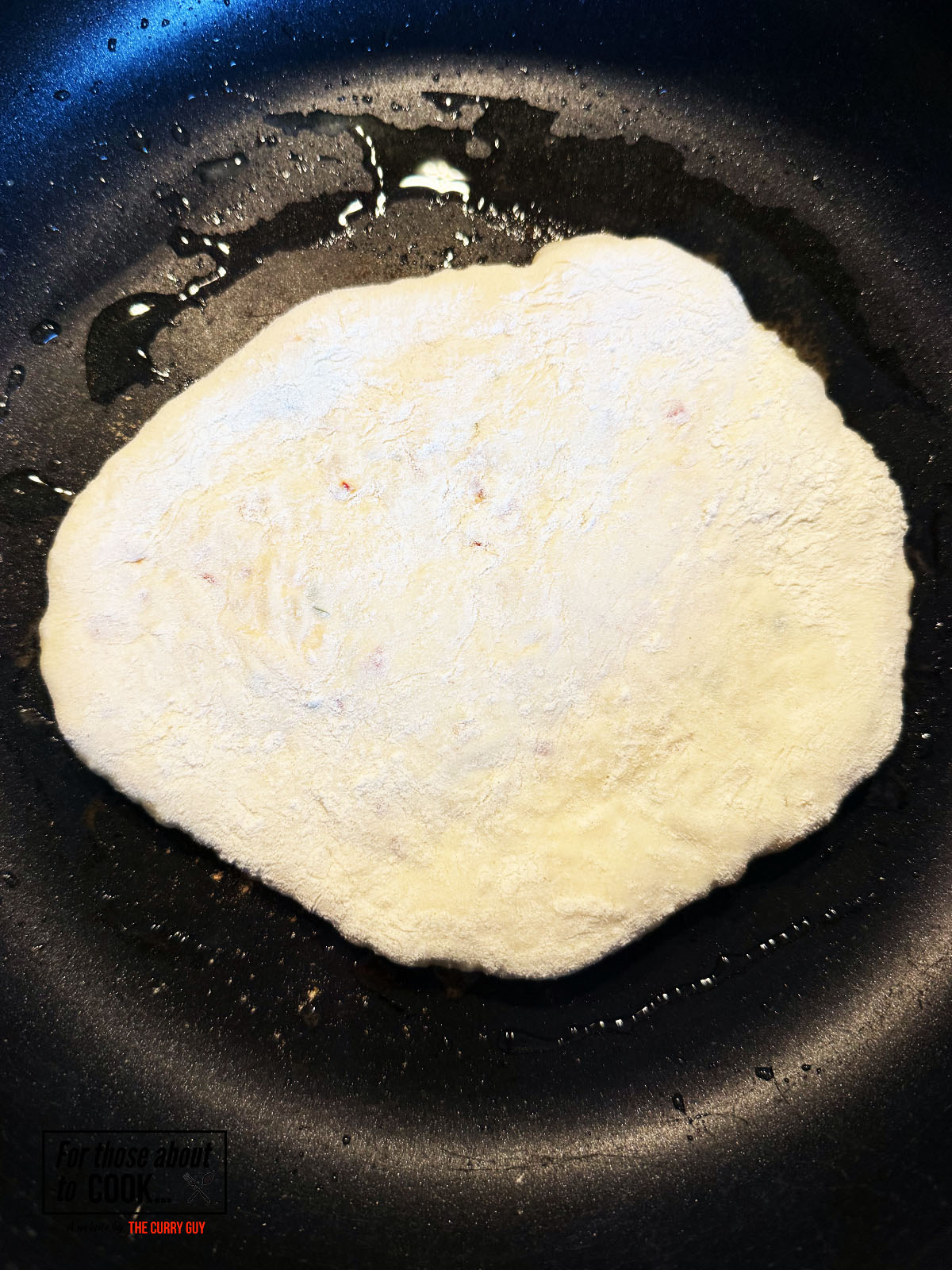 Frying the chili cheese naan in a pan with a splash of oil