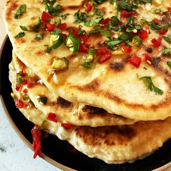 Chili cheese naans stacked and topped with garlic butter and chillies