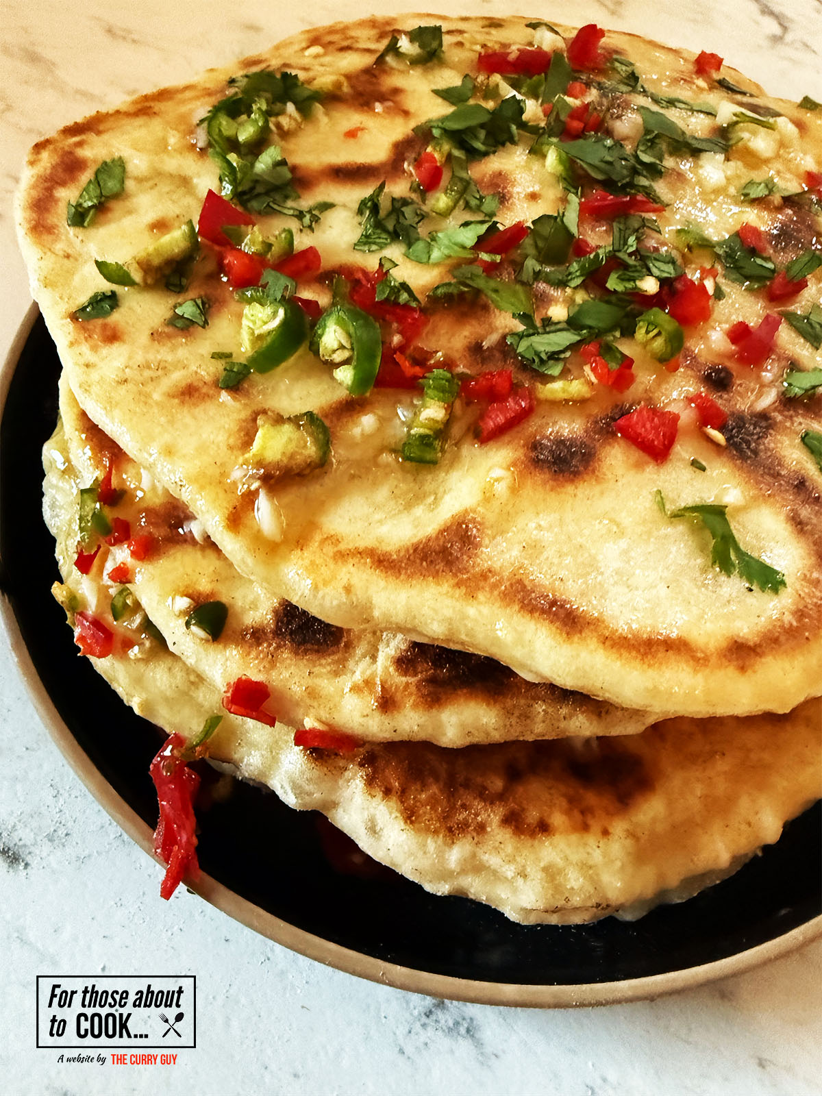Chili cheese naans stacked and topped with garlic butter and chillies
