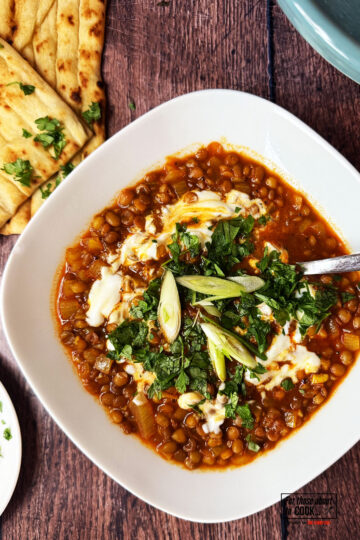 Persian lentil soup topped with yoghurt, parsley and spring onion