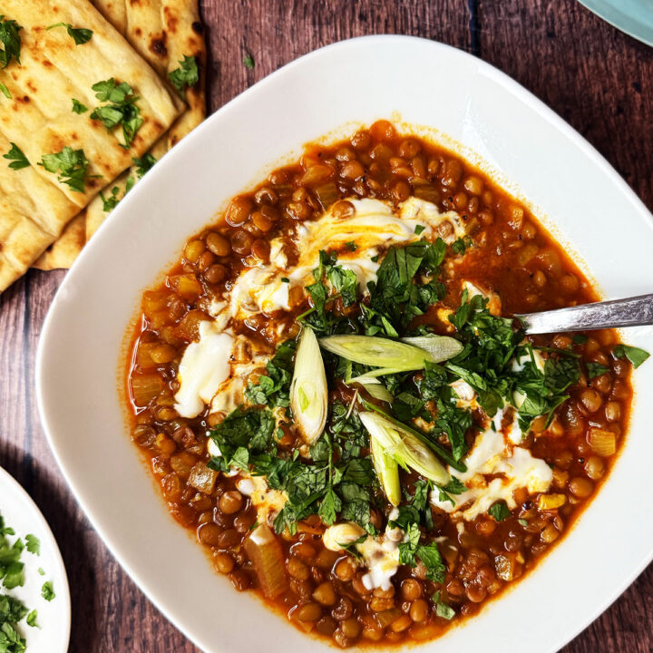 Persian lentil soup topped with yoghurt, parsley and spring onion