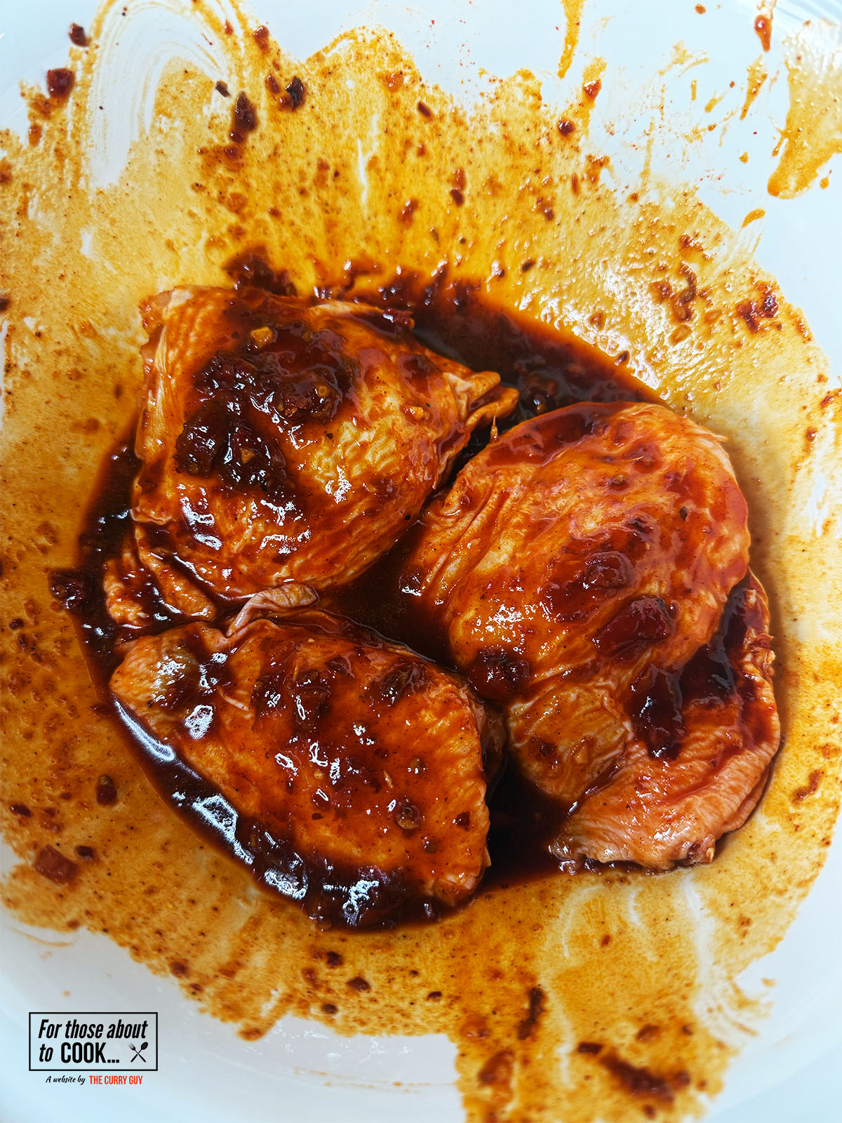 Skin on chicken thighs marinating in harissa and honey glaze