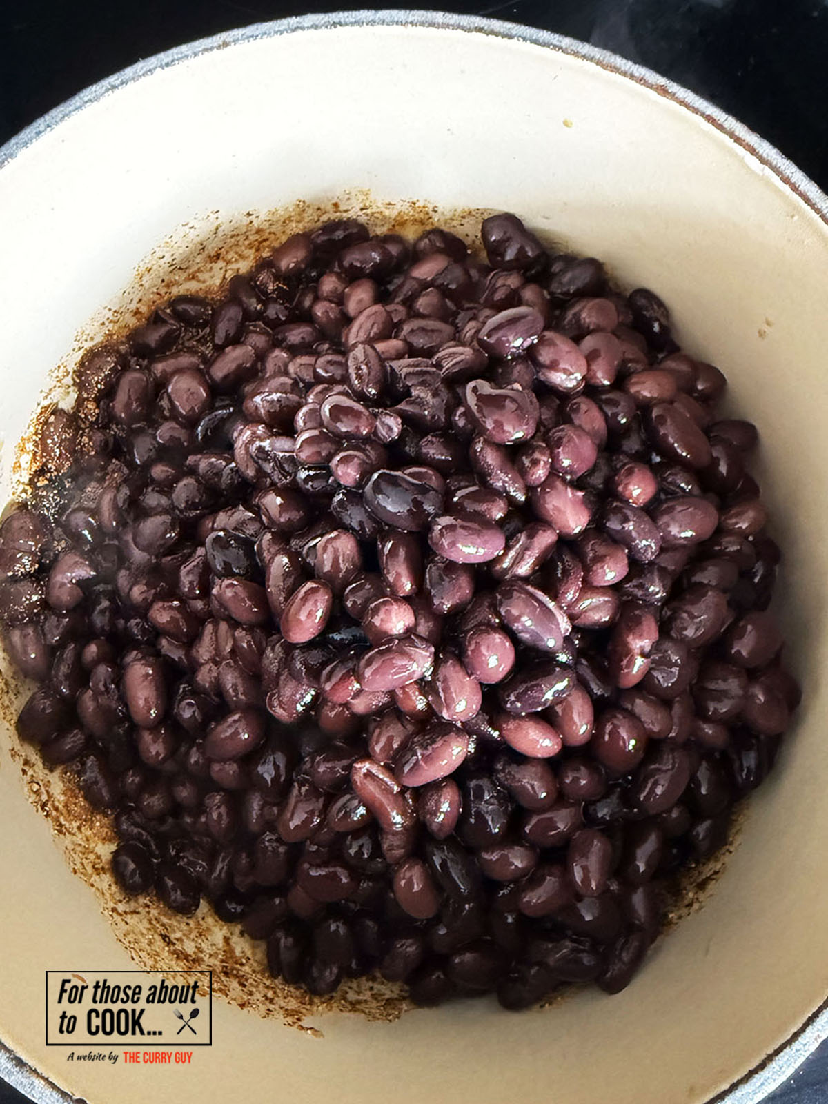 Black beans added to the pot with lard and spices