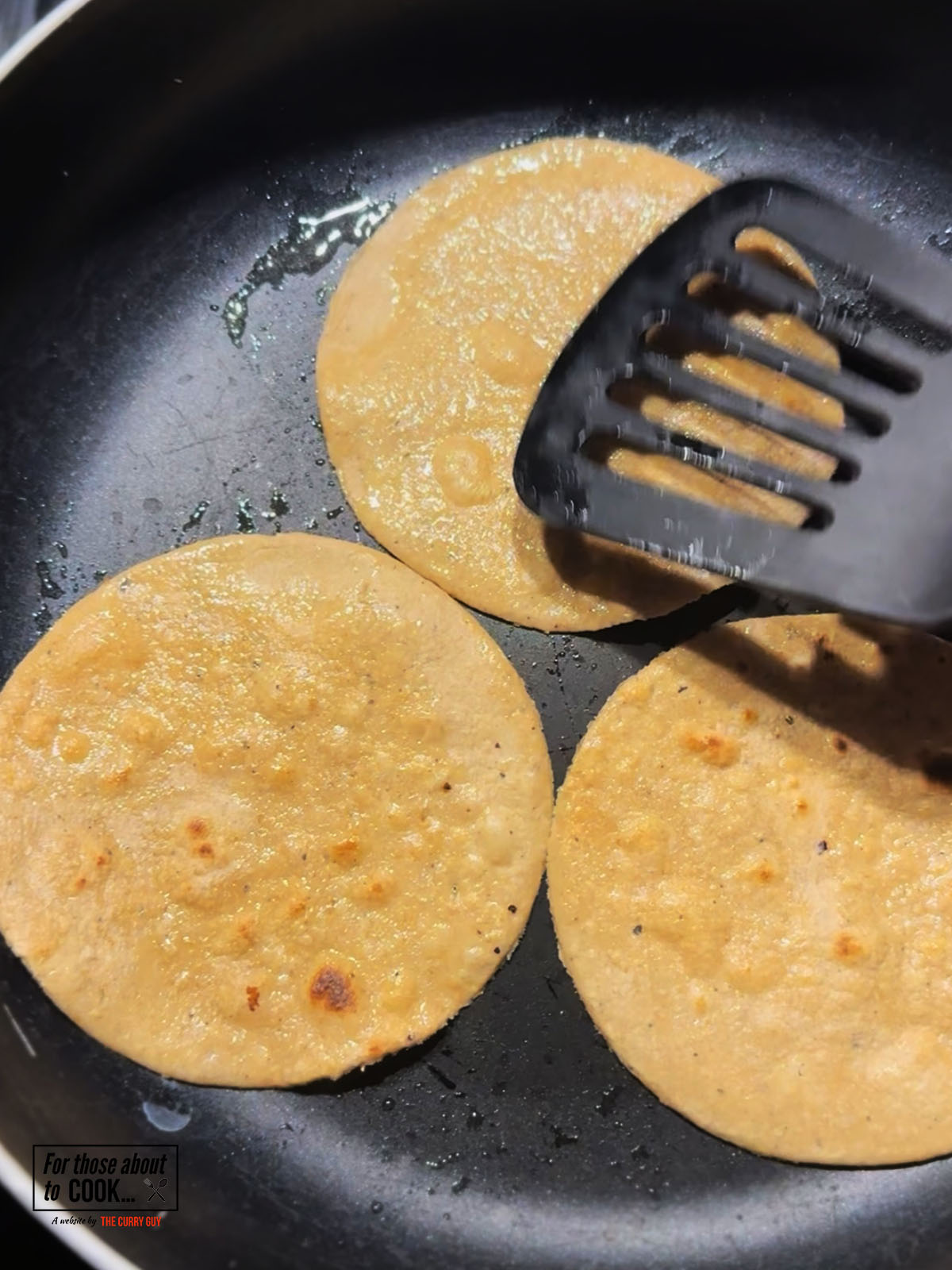 Corn tortillas frying in a pan