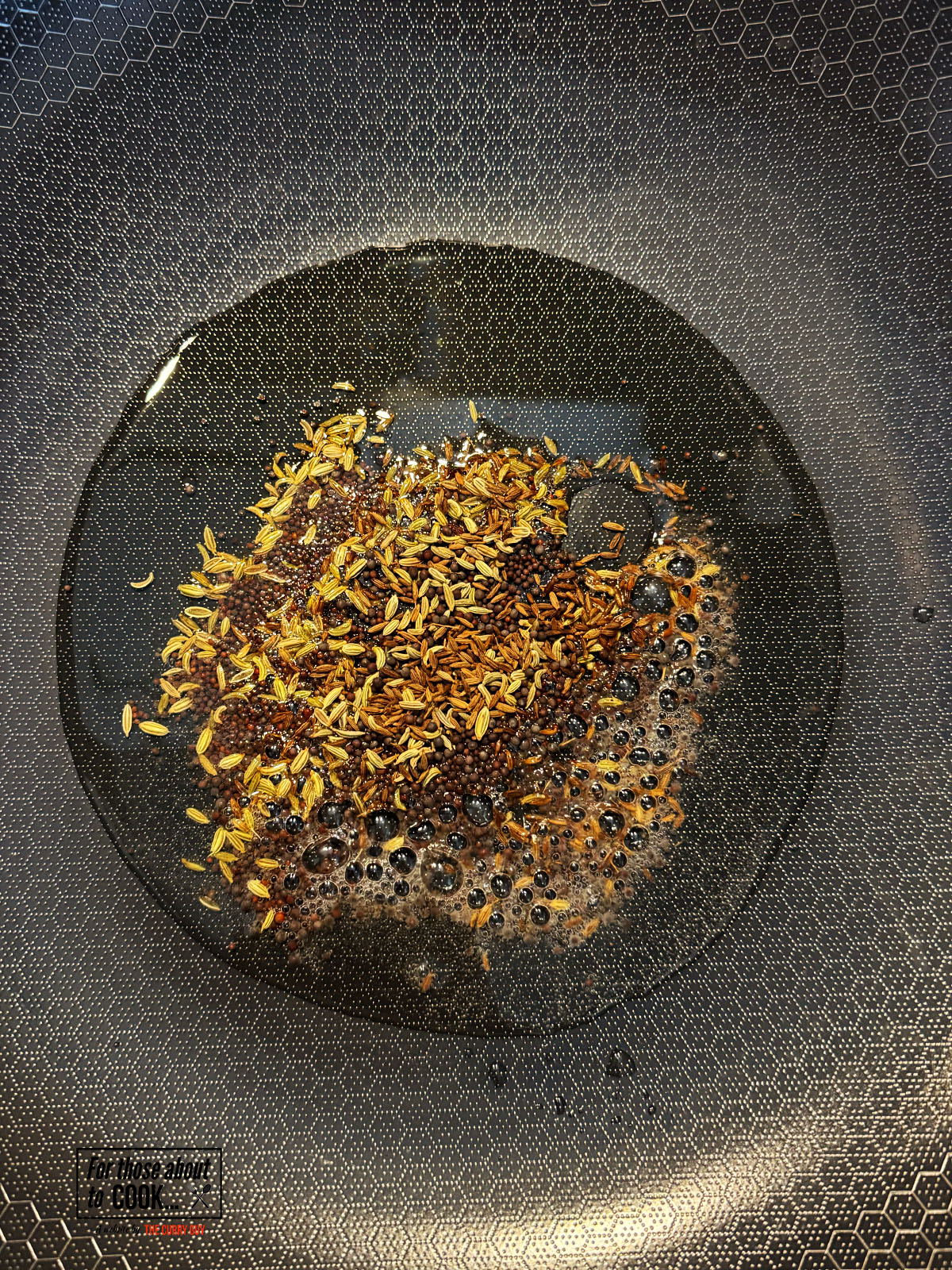 Mustard, fennel, nigella and cumin seeds toasting in a pan