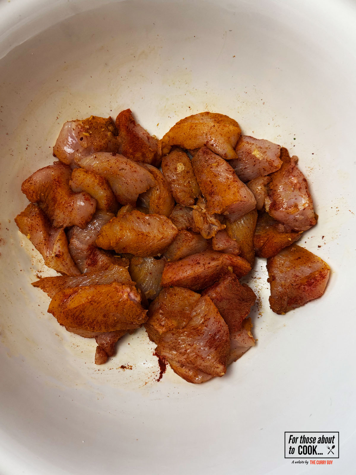 Chicken marinating with spices in a bowl