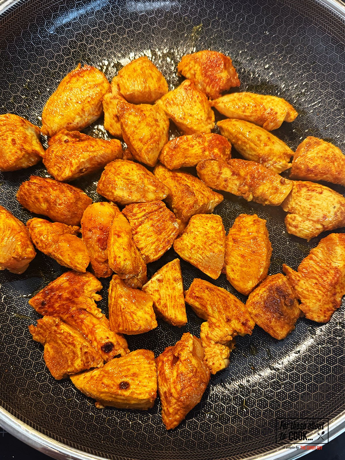 Chicken browned in a pan with spices