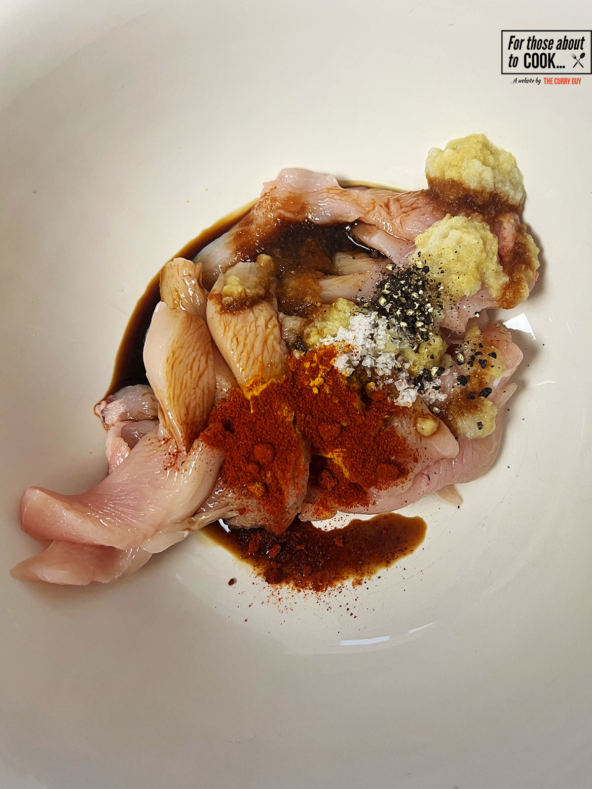 Spices added to a bowl with sliced chicken breast