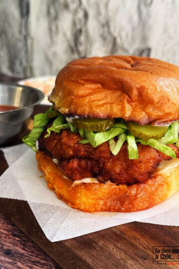 Nashville hot chicken burger served with hot sauce and topped with pickles and lettuce
