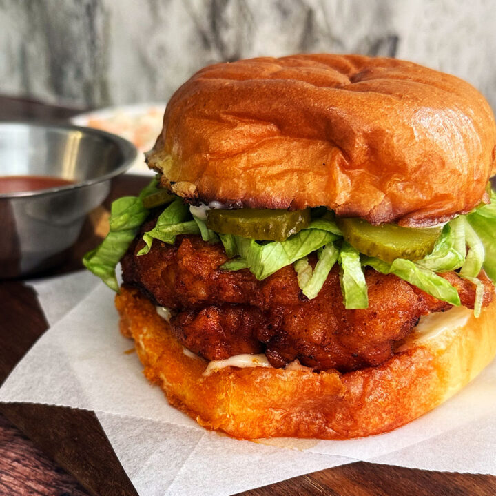 Nashville hot chicken burger served with hot sauce and topped with pickles and lettuce