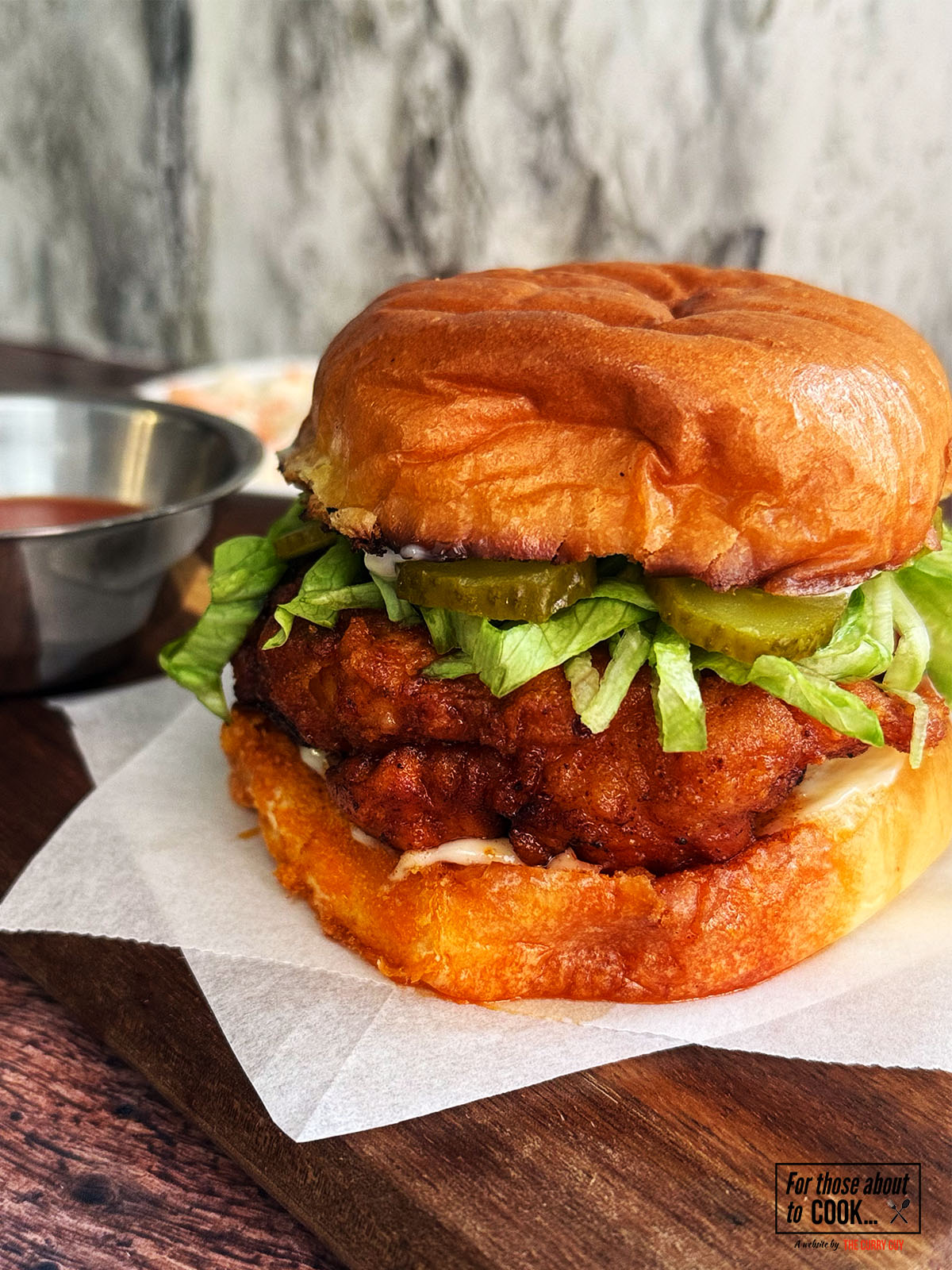 Nashville hot chicken burger served with hot sauce and topped with pickles and lettuce