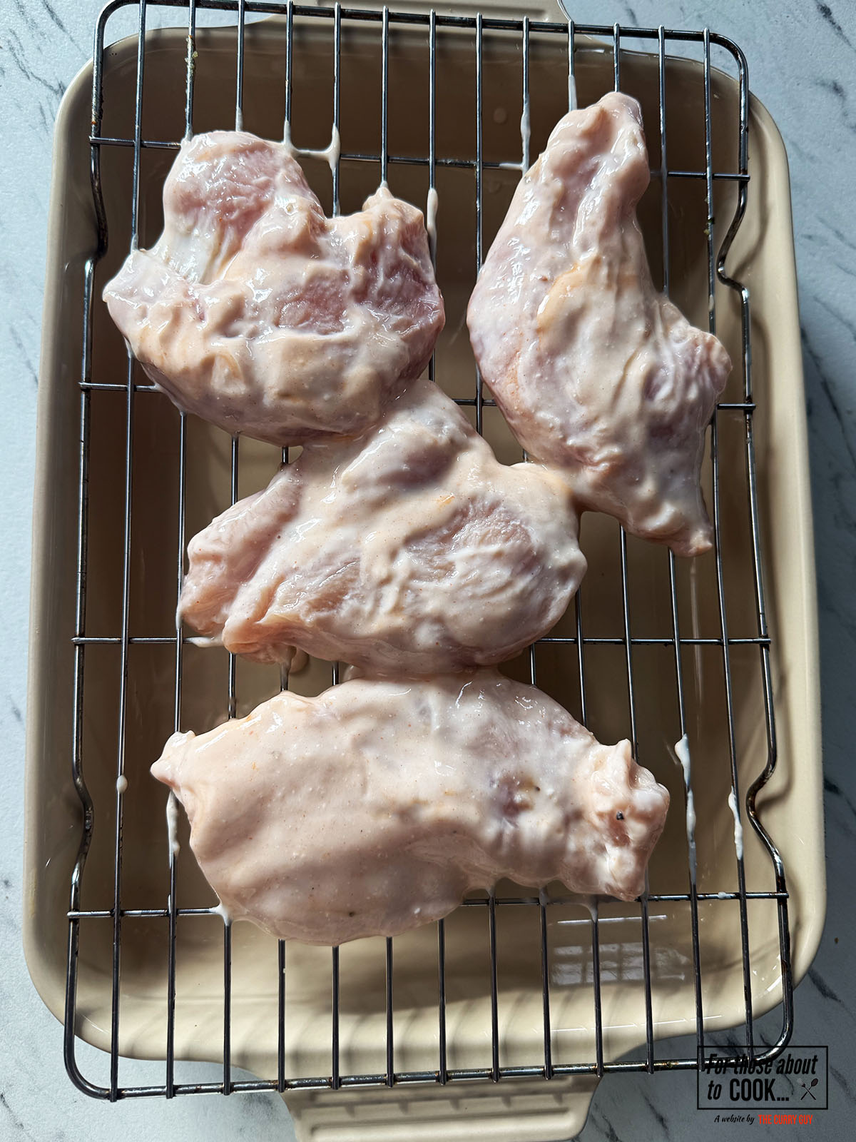Buttermilk drenched chicken breasts on a drip rack