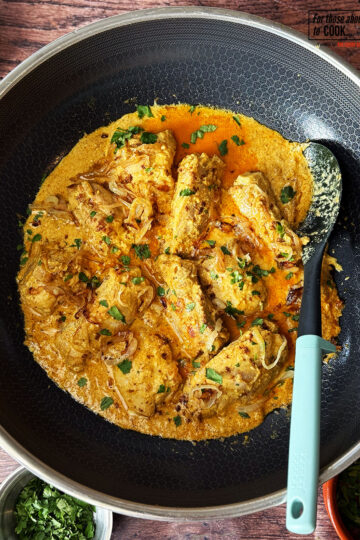 Nizami chicken curry served in the pan with fried onions and coriander