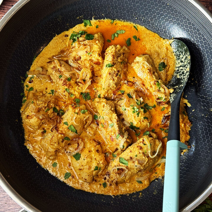 Nizami chicken curry served in the pan with fried onions and coriander