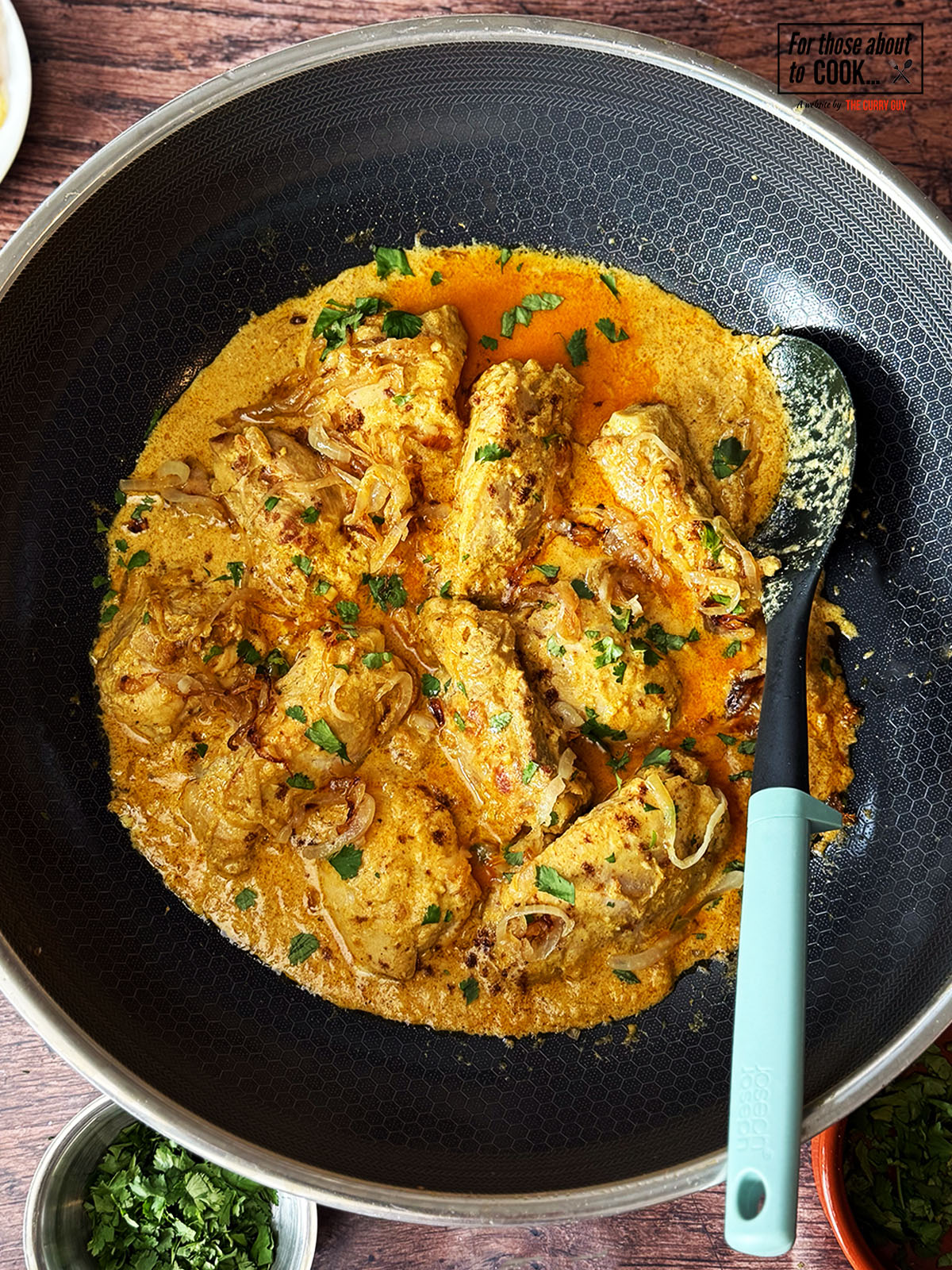 Nizami chicken curry served in the pan with fried onions and coriander