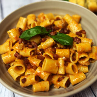 Pasta alla zozzona served in a bowl topped with pancetta and basil