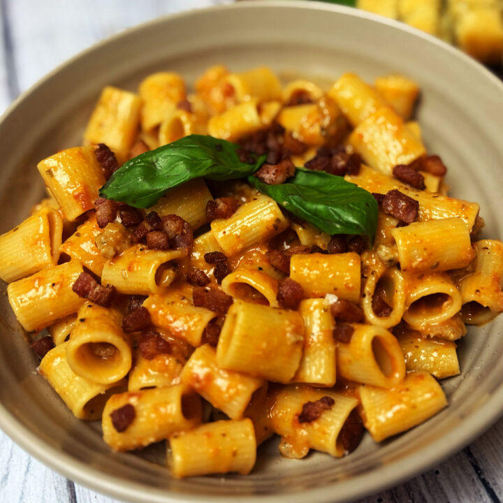 Pasta alla zozzona served in a bowl topped with pancetta and basil