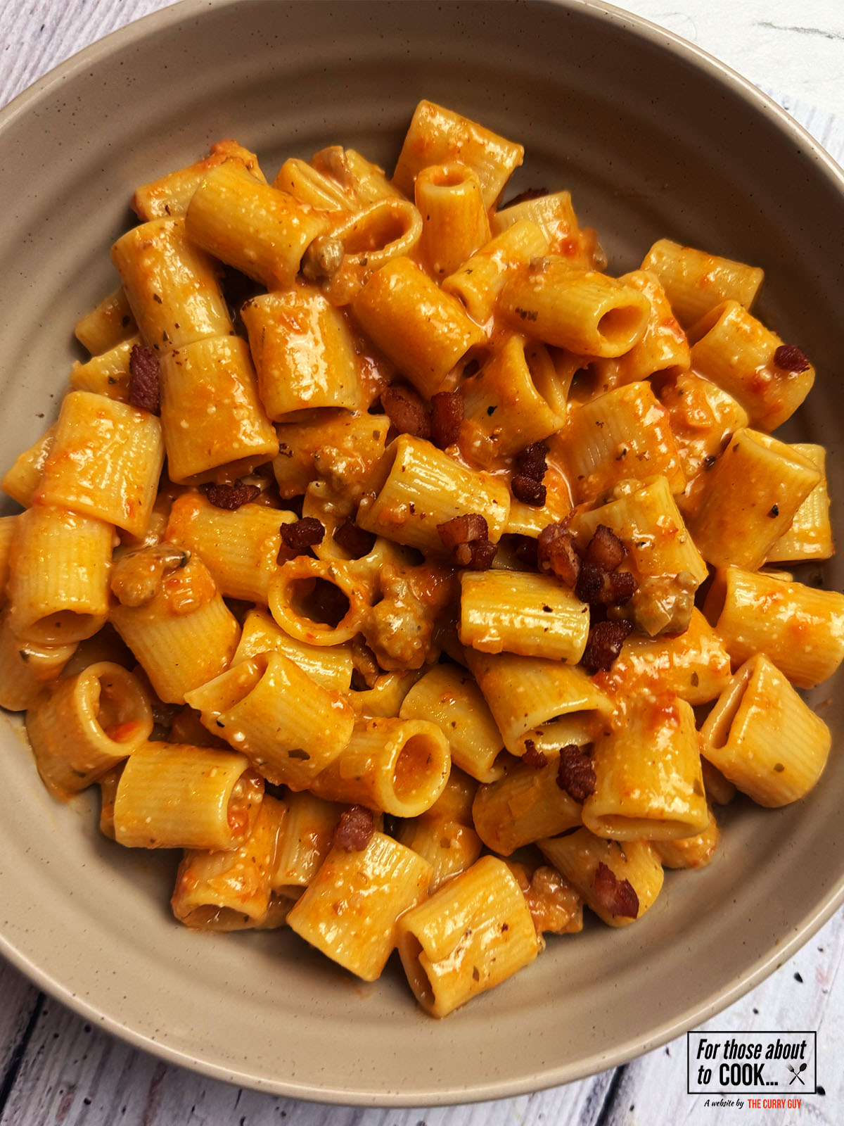 Pasta alla zozzona served in a bowl and topped with pancetta 