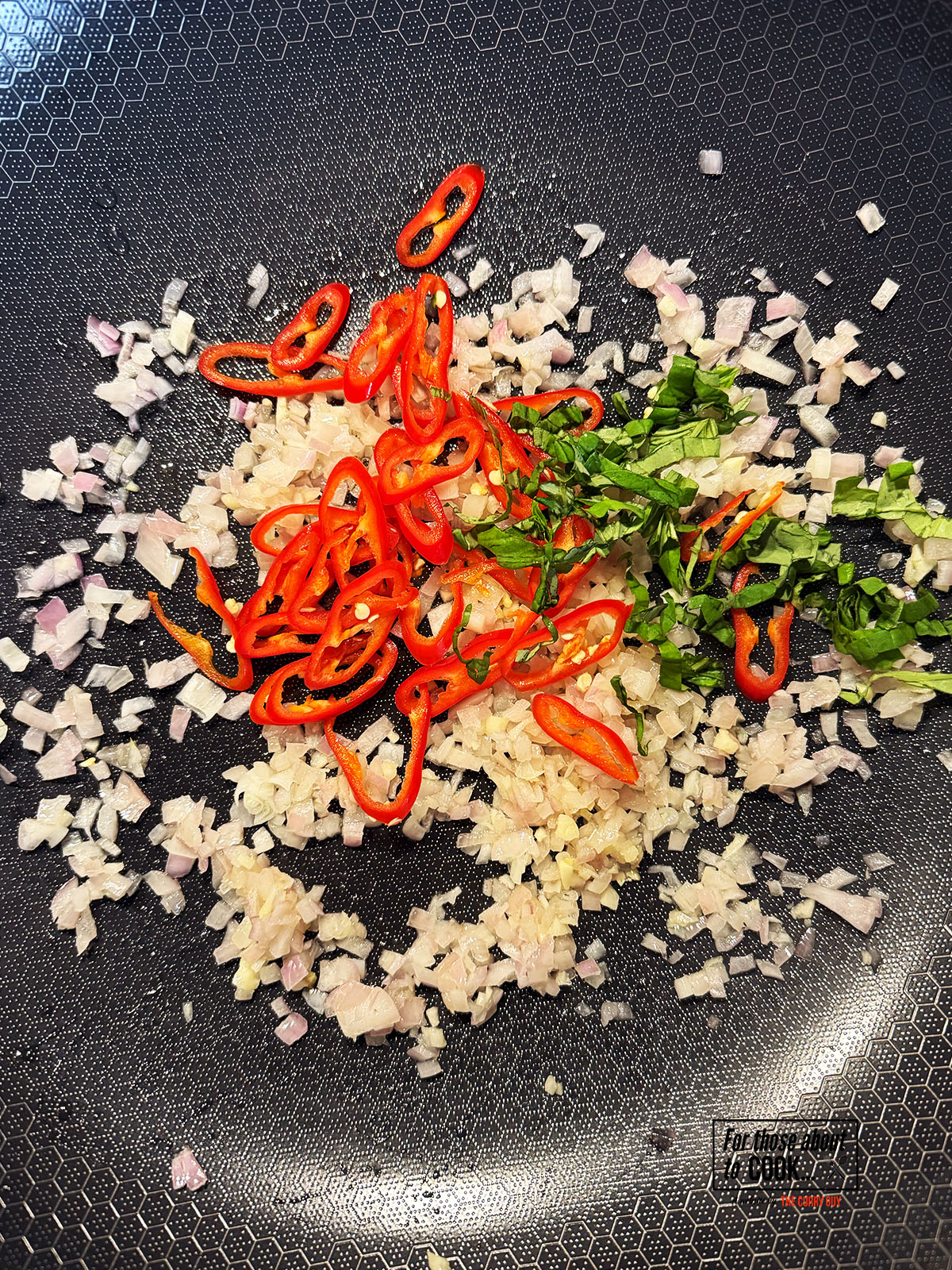Fresh chillies and shredded basil added to the pan