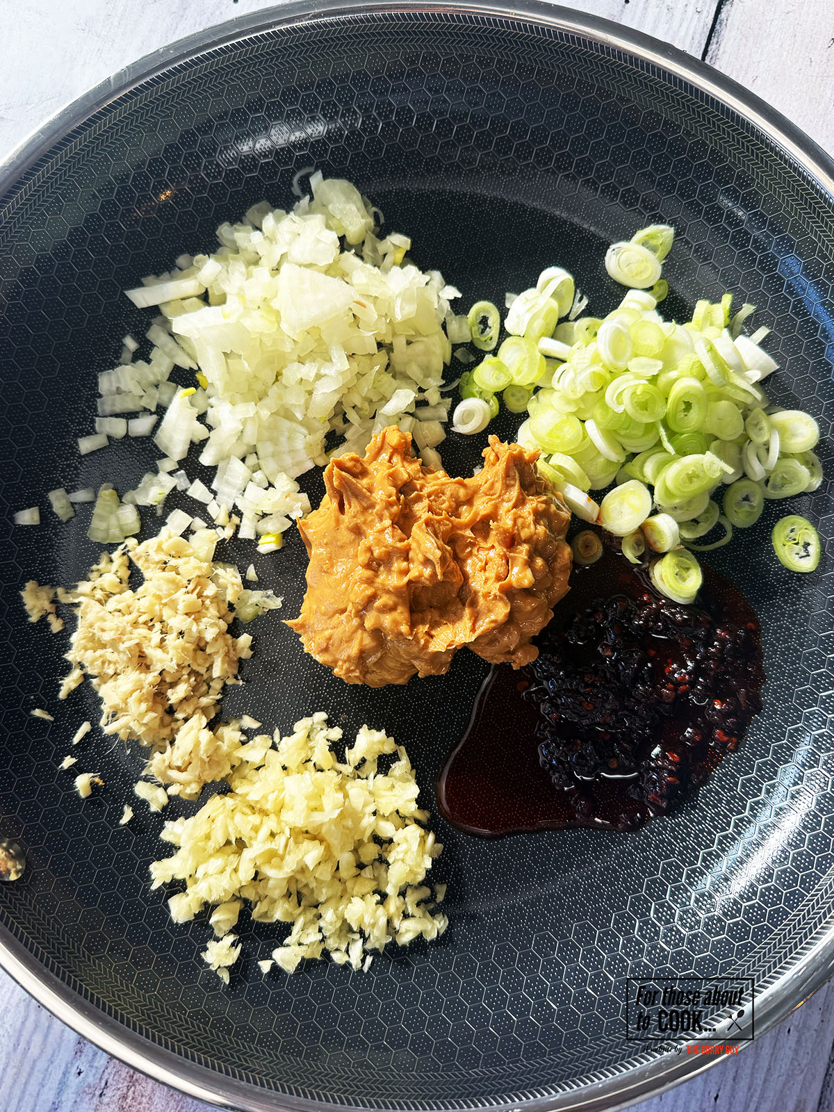 Garlic, ginger, spring onion, peanut butter, chili crisp oil and shallots in a pan