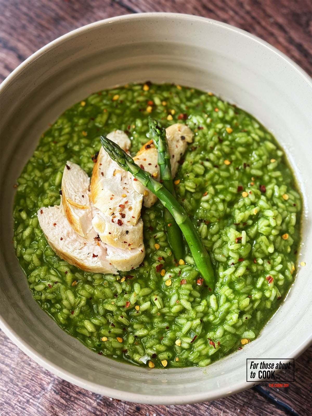 Risotto verde served with sliced chicken and asparagus sprigs