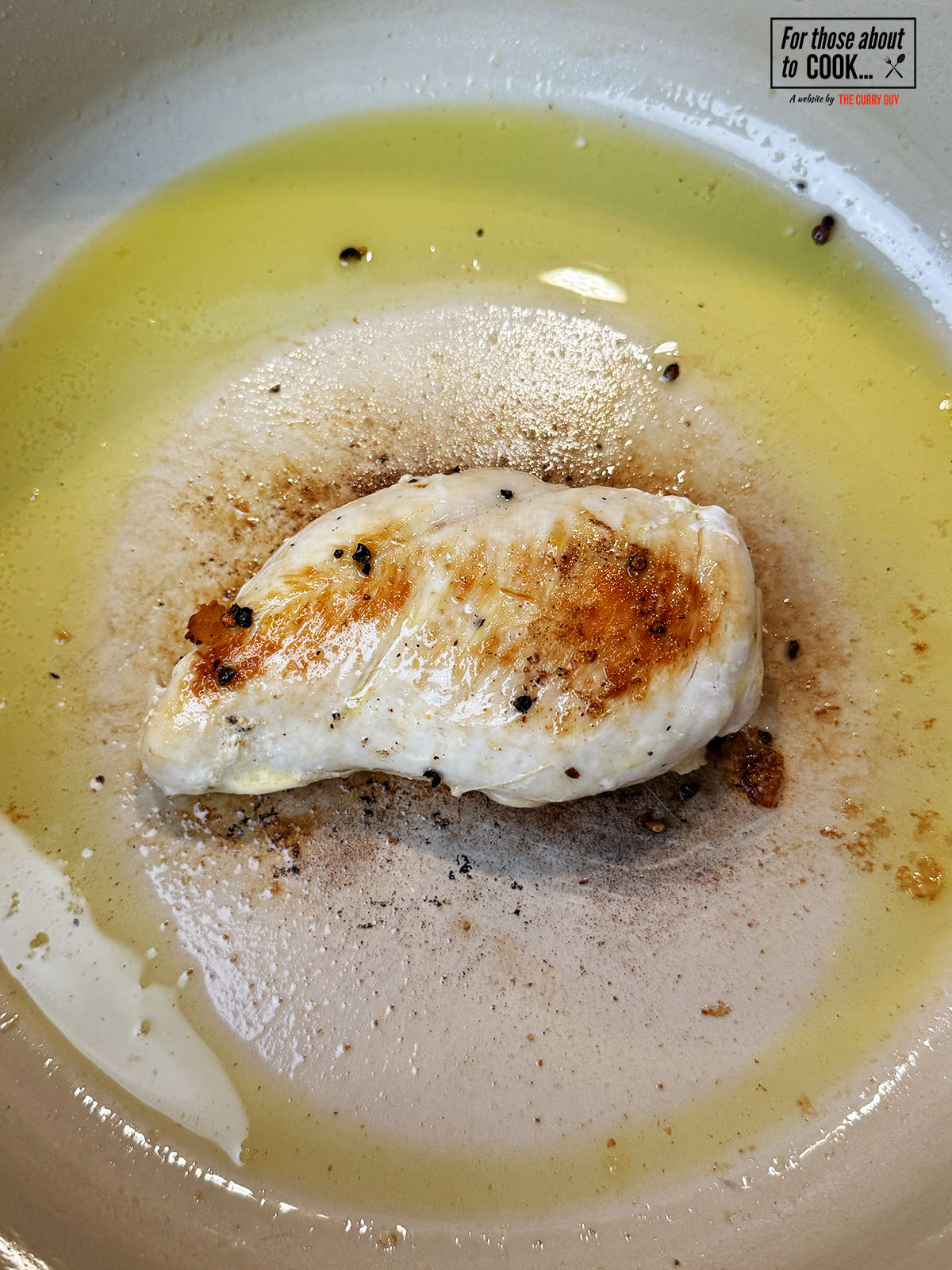 Chicken breast browning and cooking in a pan with olive oil